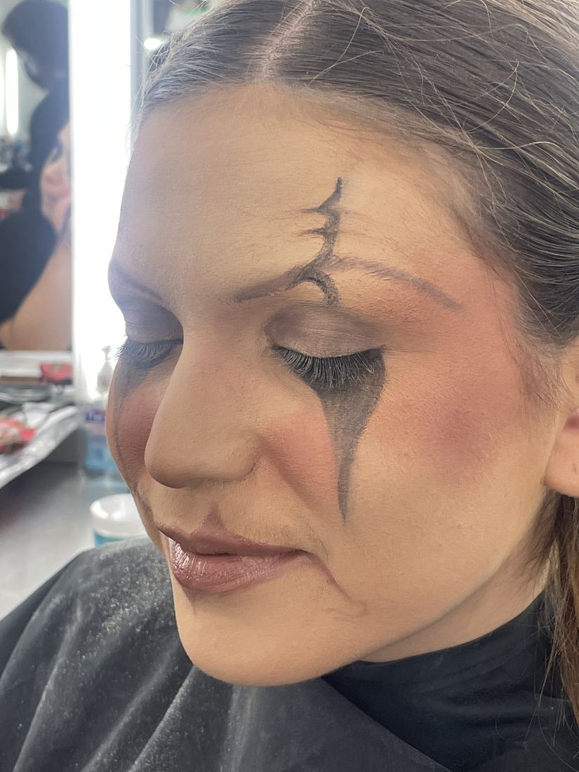 Greyscale character makeup with a painted scar and contoured hollows, eyes closed