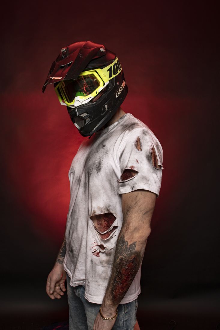 Motocross crash character in a helmet and torn shirt with prosthetic wounds